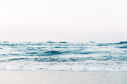 kleine Wellen treffen auf einen Strand bei Sonnenaufgang